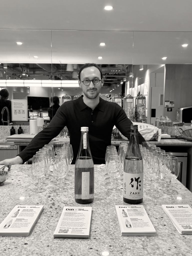Luca Snape posé devant des bouteilles de saké japonais